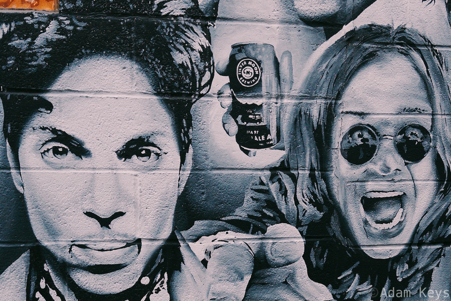 A black-and-white mural on a brick wall features Prince and Ozzy Osbourne